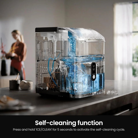 Clear kitchen appliance with blue liquid on a countertop, woman in the background