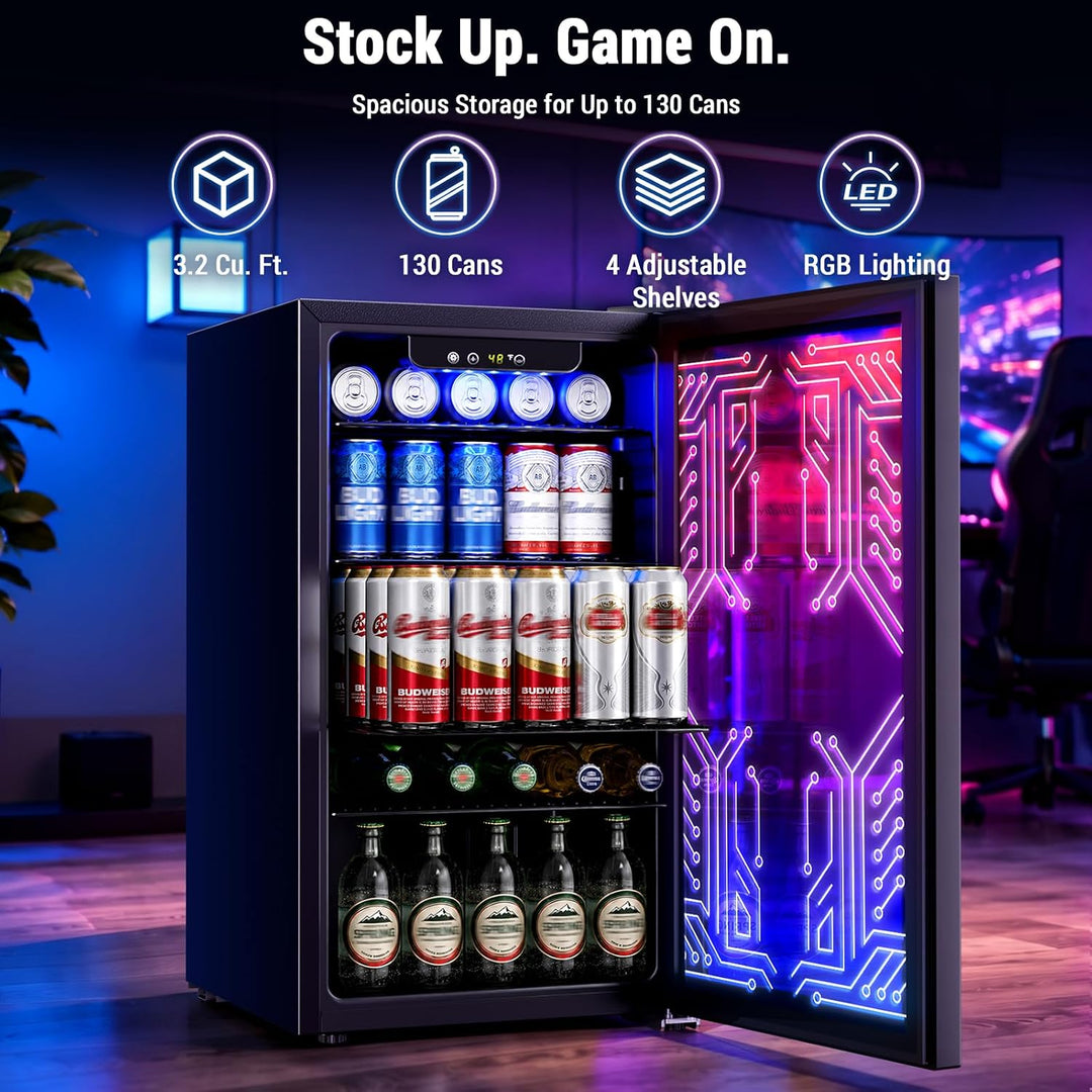 A black mini beverage refrigerator with a glass door, illuminated by blue and pink LED lighting with circuit-board graphics. The refrigerator is stocked with canned and bottled drinks on three shelves, set against a blurred gaming room background.