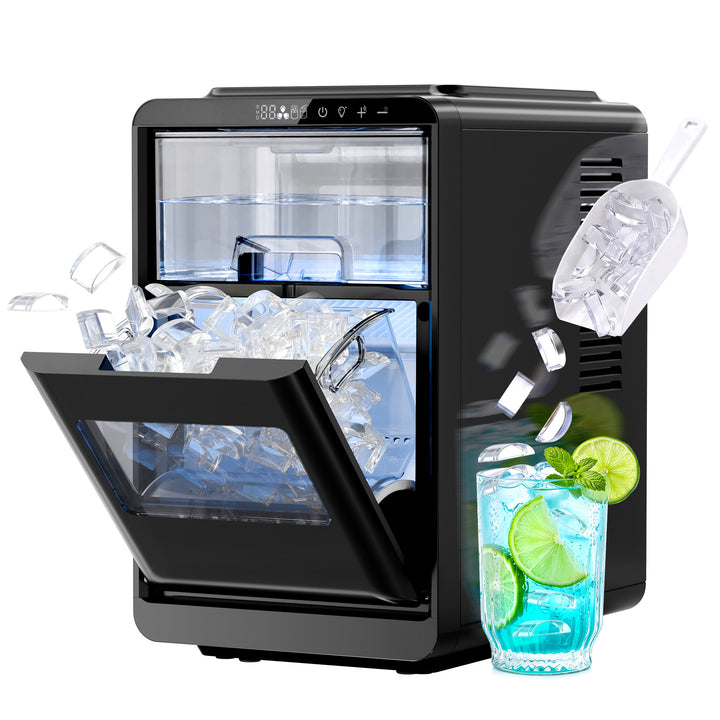 A black countertop ice maker machine with its door open, shown with ice cubes and a glass of blue drink with lime slices floating around it on a white background.