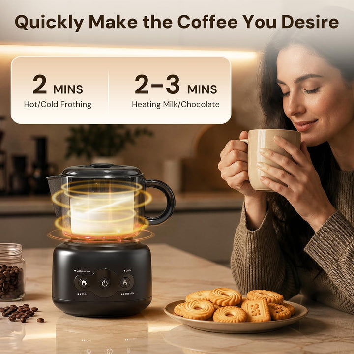 A countertop coffee maker with a black base and clear glass chamber sits on a kitchen counter next to a plate of cookies, with a woman in the background holding a mug. Text at the top reads 'Quickly Make the Coffee You Desire' with feature callouts for frothing and heating milk/chocolate.